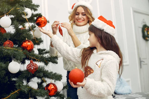 Anne ve tatlı kızı Noel ağacının yanında duruyor.