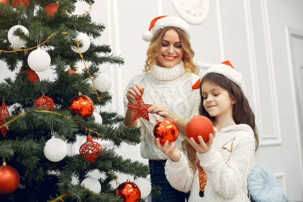 Anne ve tatlı kızı Noel ağacının yanında duruyor.