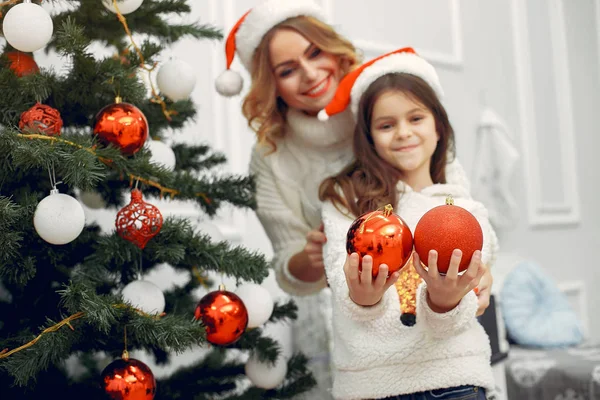 Anne ve tatlı kızı Noel ağacının yanında duruyor.