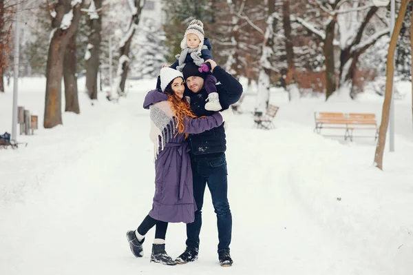 Liten flicka med föräldrar i en vinterpark — Stockfoto