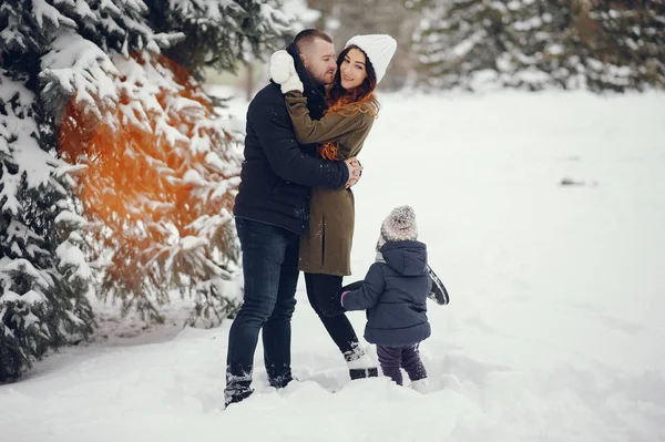 Liten flicka med föräldrar i en vinterpark — Stockfoto