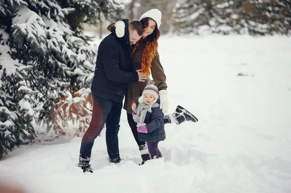 Маленька дівчинка з батьками в зимовому парку — стокове фото