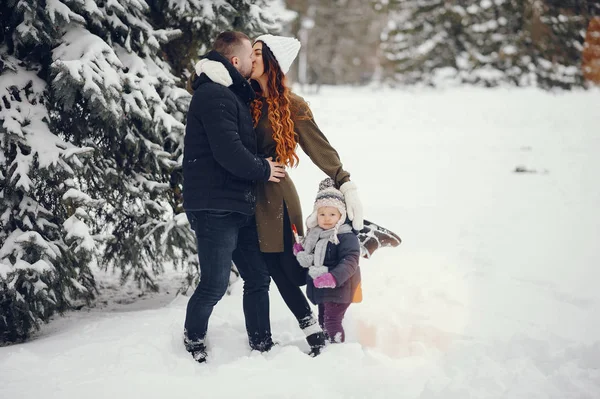 Liten flicka med föräldrar i en vinterpark — Stockfoto