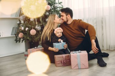 Aile Noel ağacının yanında oturuyor.