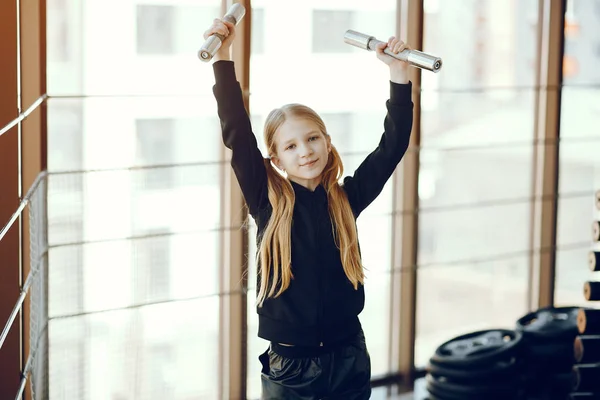 Ein schönes kleines Mädchen ist in einem Fitnessstudio beschäftigt — Stockfoto