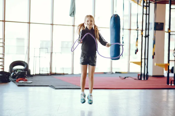 Ein schönes kleines Mädchen ist in einem Fitnessstudio beschäftigt — Stockfoto