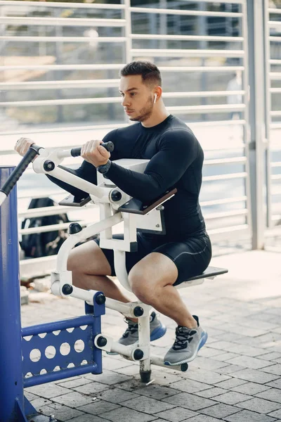 Bonito homem treinando em um parque de verão — Fotografia de Stock