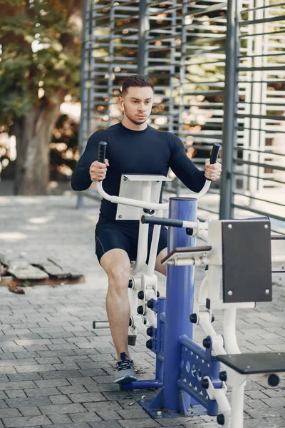 Bonito homem treinando em um parque de verão — Fotografia de Stock