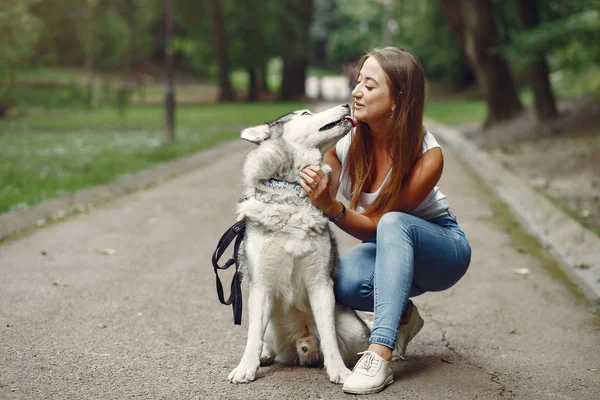 Девушка в весеннем парке играет с милой собакой — стоковое фото