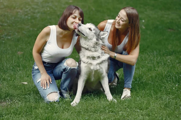 Dwie dziewczyny w wiosennym parku bawią się słodkim psem — Zdjęcie stockowe