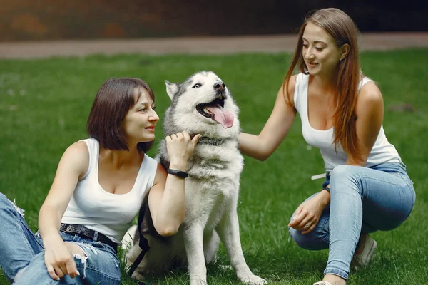 Две девушки в весеннем парке играют с милой собакой — стоковое фото