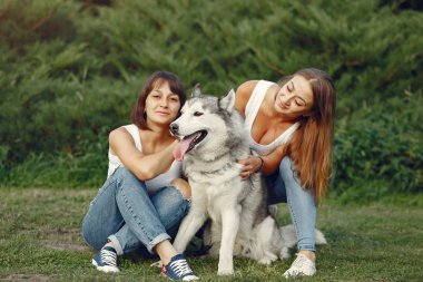 Bir bahar parkında iki kız sevimli bir köpekle oynuyor.