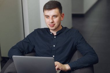 Ofiste çalışan şık bir iş adamı ve dizüstü bilgisayarı kullanıyor.