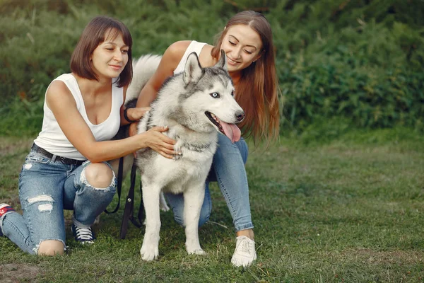 Dua gadis di taman musim semi bermain dengan anjing lucu — Stok Foto