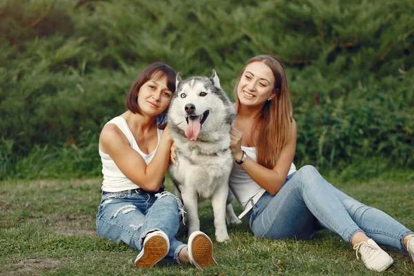 Två tjejer i en vårpark leker med söt hund — Stockfoto