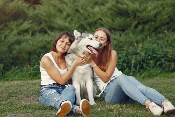 Duas meninas em um parque de primavera brincando com o cão bonito — Fotografia de Stock