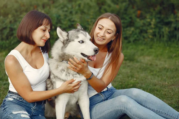 Dwie dziewczyny w wiosennym parku bawią się słodkim psem — Zdjęcie stockowe