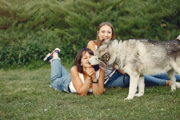 Dwie dziewczyny w wiosennym parku bawią się słodkim psem — Zdjęcie stockowe
