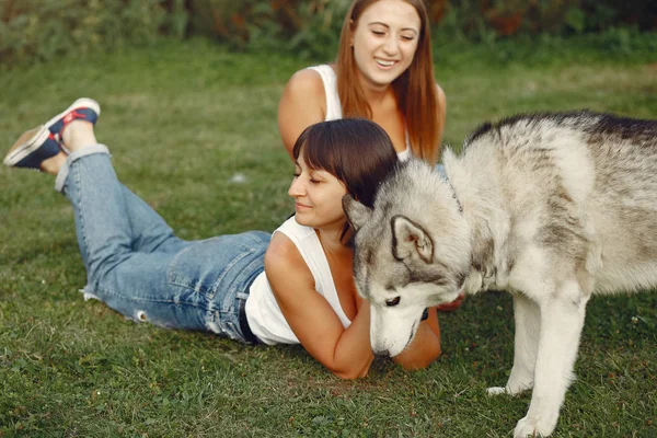 Dua gadis di taman musim semi bermain dengan anjing lucu — Stok Foto