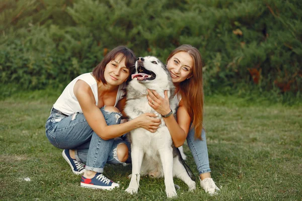 Duas meninas em um parque de primavera brincando com o cão bonito — Fotografia de Stock