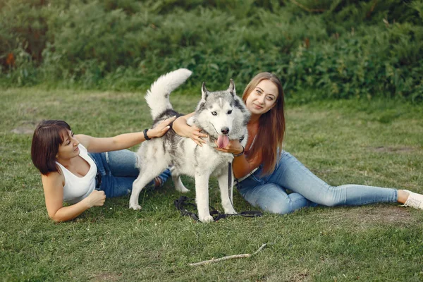 Duas meninas em um parque de primavera brincando com o cão bonito — Fotografia de Stock