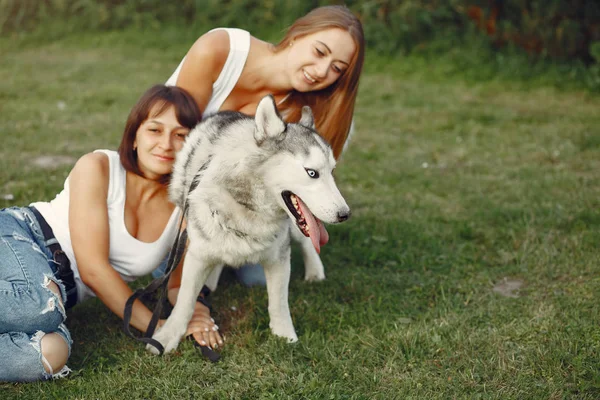 Дві дівчини в весняному парку грають з милою собакою — стокове фото