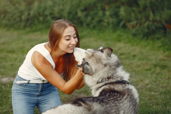 Девушка в весеннем парке играет с милой собакой — стоковое фото