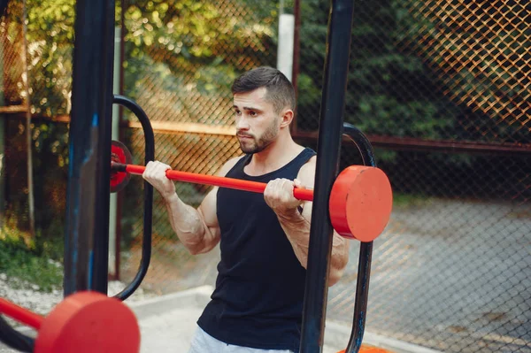 Bonito homem treinando em um parque de verão — Fotografia de Stock