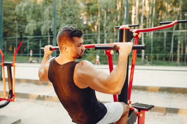 Bonito homem treinando em um parque de verão — Fotografia de Stock