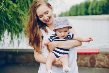 Anne ve oğlu parkta dinleniyor ve nehirde yürüyor..