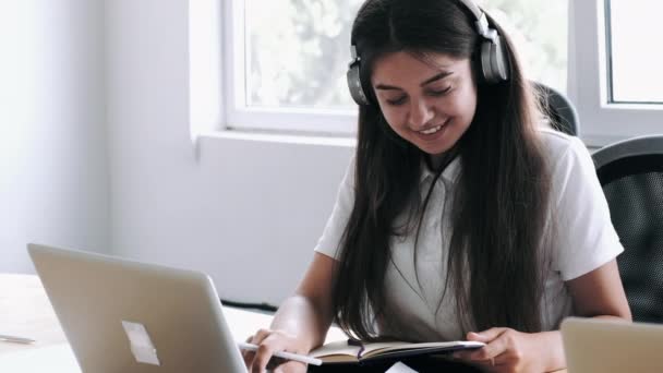 Brunett kvinna i hörlurar arbetar med uppgift i moderna kontor — Stockvideo