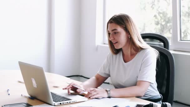 Kvinna med bärbar dator nära fönster i vitt rum — Stockvideo