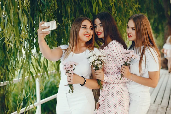 Meninas bonitas em um parque de verão com um telefone — Fotografia de Stock