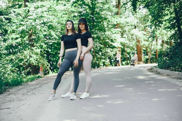 Beautiful sportsgirls in a summer sunny park — Stock Photo, Image