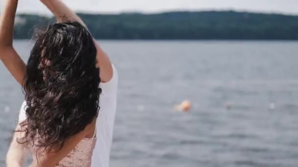 Close-up van de vrouw met donker haar dansen dicht bij het meer — Stockvideo