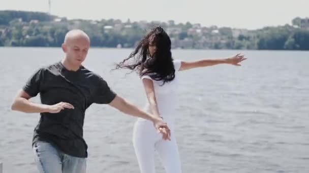 Женщина с темными волосами танцует с партнером возле озера — стоковое видео