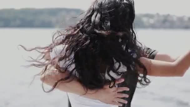 Жінка з темним волоссям танцює з партнером біля озера — стокове відео