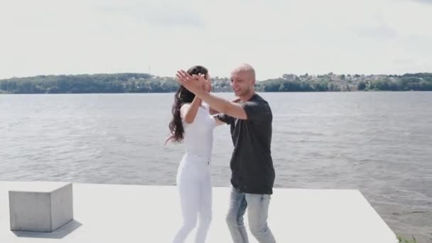 Активная пара, занимающаяся танцами возле озера — стоковое видео