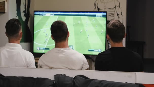 Tři přátelé sedí na gauči a dívají se na fotbal — Stock video
