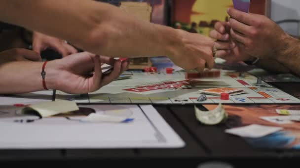 Empresa de amigos jogando monopólio no tempo livre em casa — Vídeo de Stock