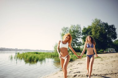 Güzel kızı olan sportif bir anne göl kenarında yürüyor.