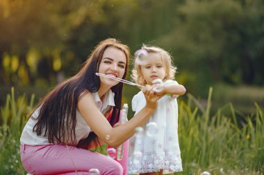 Anne ve kızı yaz parkında oynuyorlar.