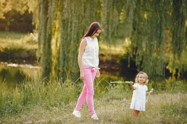Anne ve kızı yaz parkında oynuyorlar.