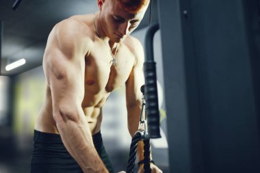 The pumped man is engaged in sports in the gym