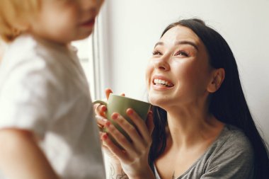 Anne ve küçük oğlu elinde çayla pencere eşiğinde oturuyorlar.