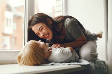 Anne ve küçük oğlu pencere eşiğinde oturuyor.