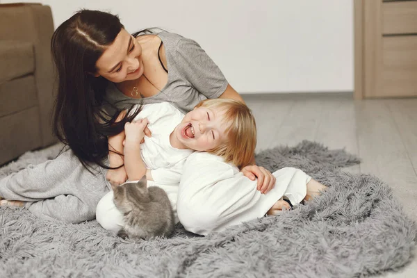 Madre e hijo pequeño diversión en casa con un gato — Foto de Stock