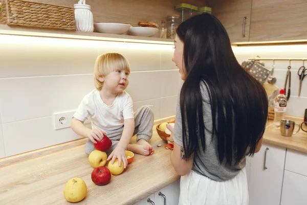 Madre con hijo pequeño comiendo frutas en una cocina — Foto de Stock