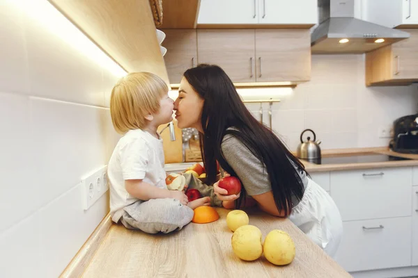 Matka s malým synem jíst ovoce v kuchyni — Stock fotografie
