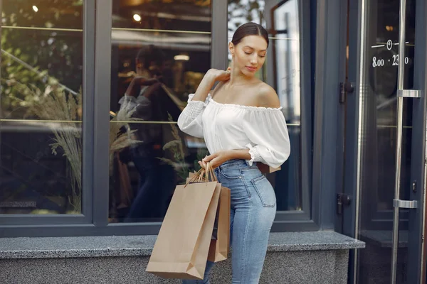 Elegante und stylische Mädchen in einer Sommerstadt mit Einkaufstaschen — Stockfoto